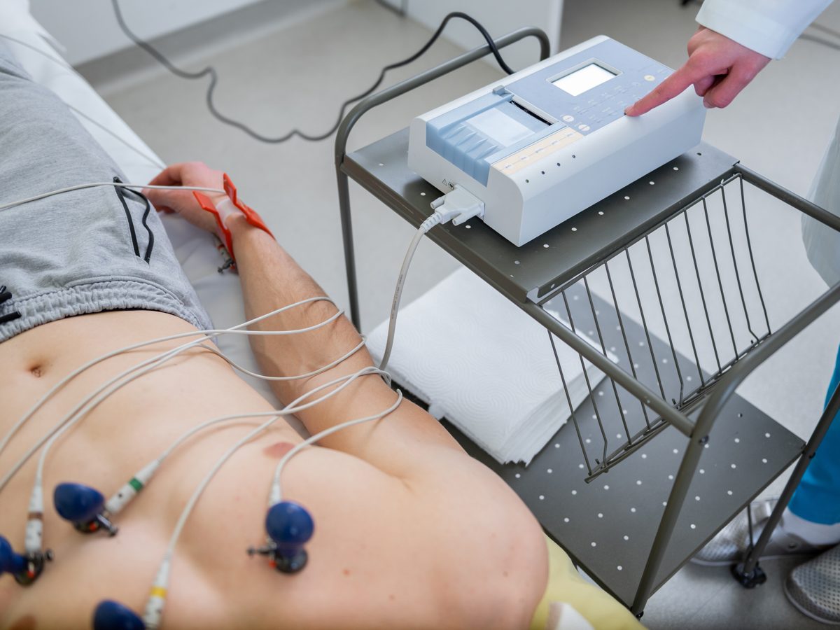 Paciente realizando eletrocardiograma com eletrodos conectados ao aparelho