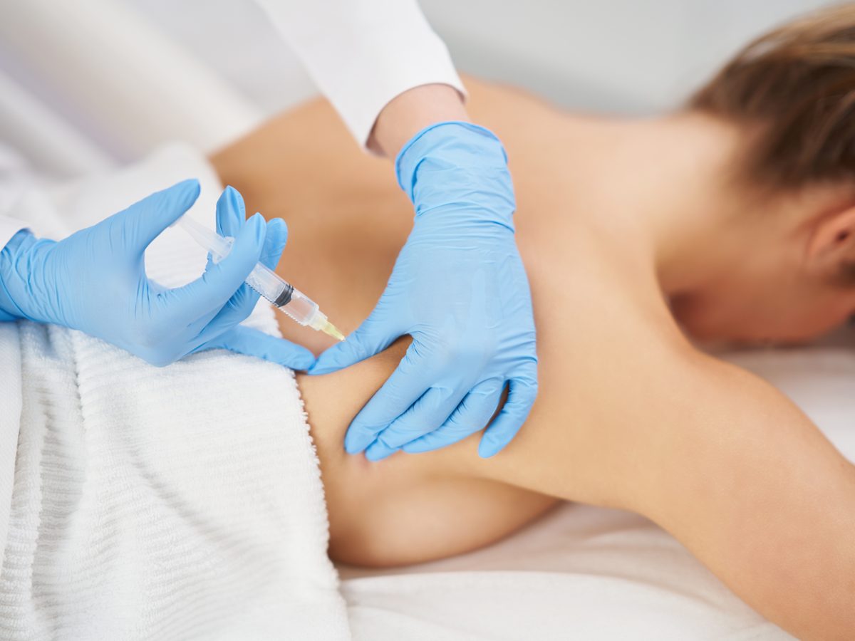 Médica realizando procedimento na região lombar de paciente deitada
